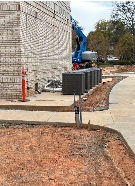 Row of condensing units set on a concrete curb at a commercial building