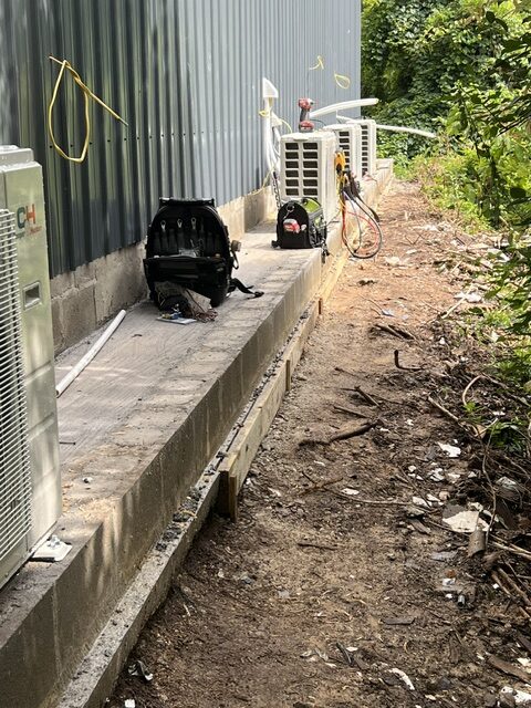 Condensing units set on a concrete pad along the exterior of a commercial building