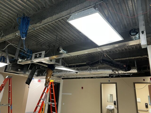Overhead ductwork being installed above the ceiling grid in a commercial fit-out