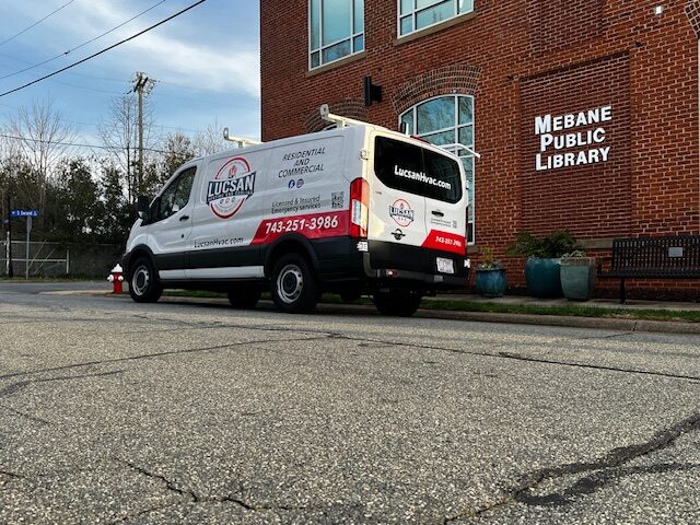 Lucsan Heating and Cooling service van parked outside the Mebane Public Library